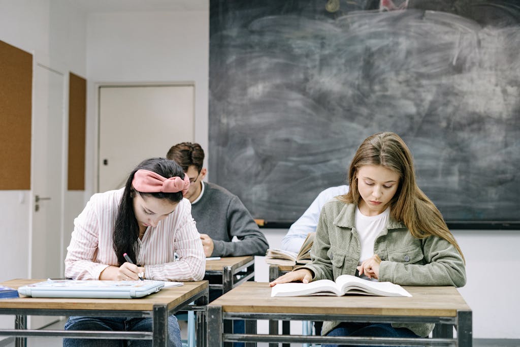 Young students studying in a classroom, focused on reading and writing assignments.